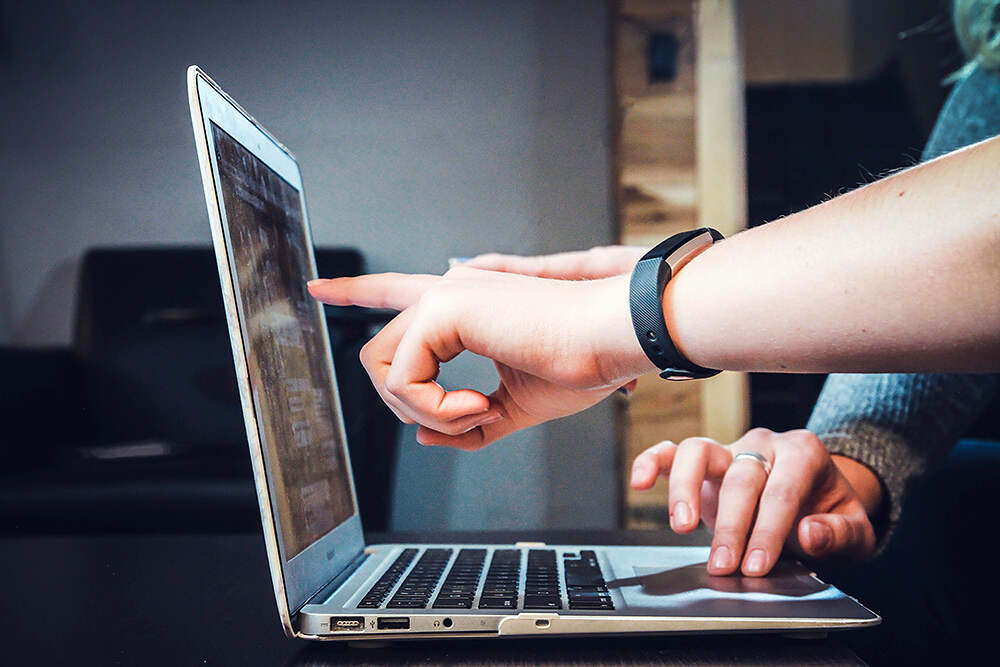 people pointing at laptop screen