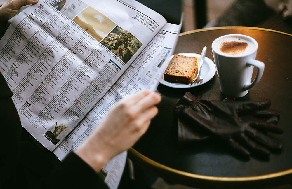 woman reading newspaper at a cafe